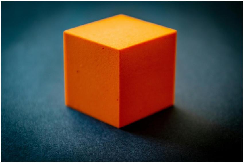 Close-up of an orange foam cube on a dark surface,