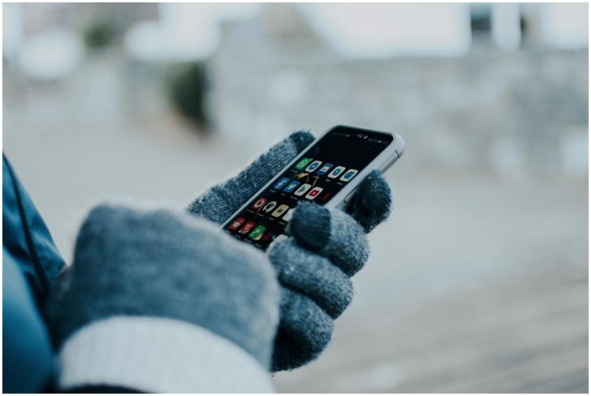 Close-up of hands using smartphone with gloves in