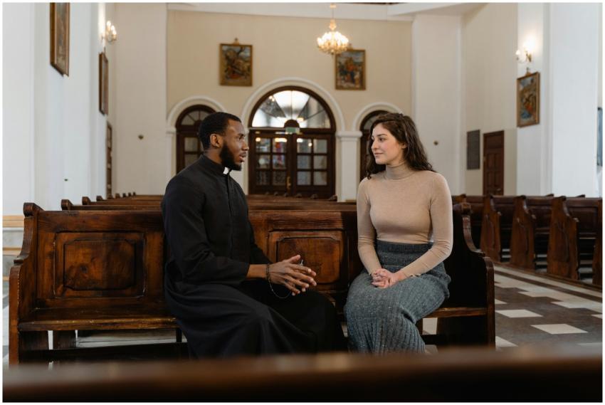 A priest and a woman sit and converse inside a bea