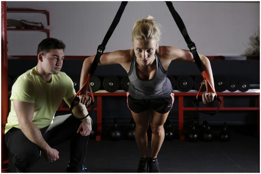 A woman performing strength training with a traine