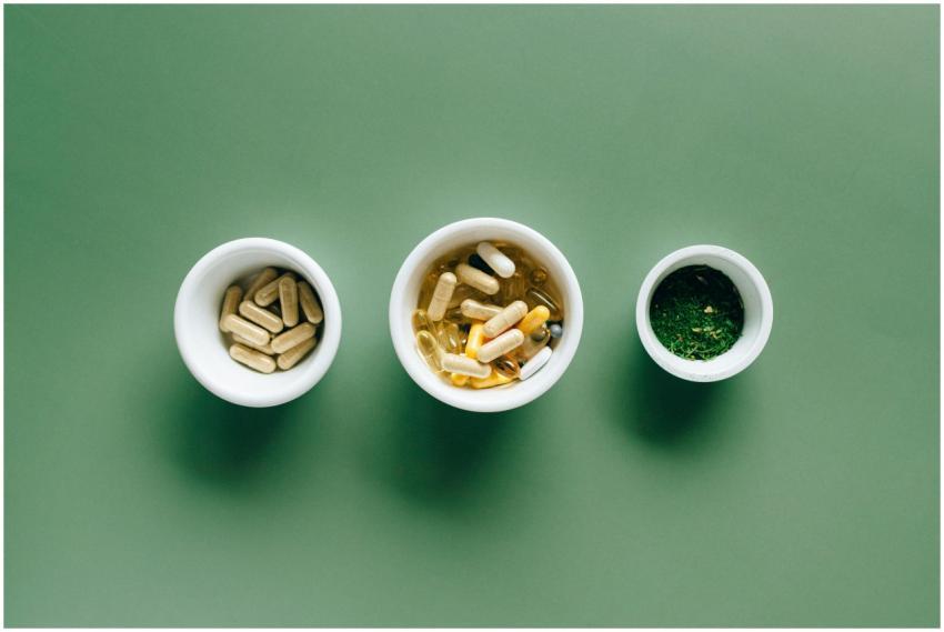 Top view of bowls with capsules, herbs, and supple