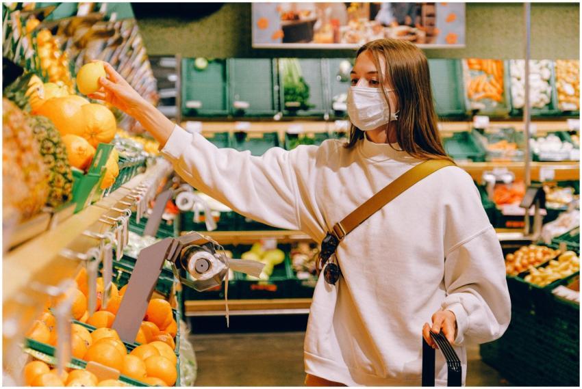 Woman wearing a mask selecting fruit at a grocery