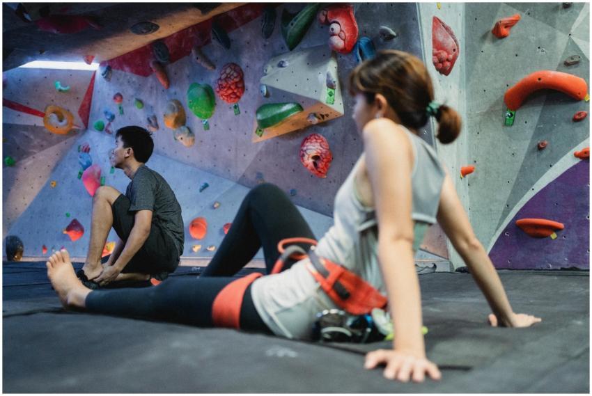 Two young adults resting on mats in an indoor boul
