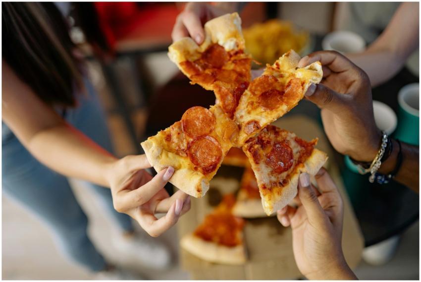 Close-up of diverse hands holding pepperoni pizza