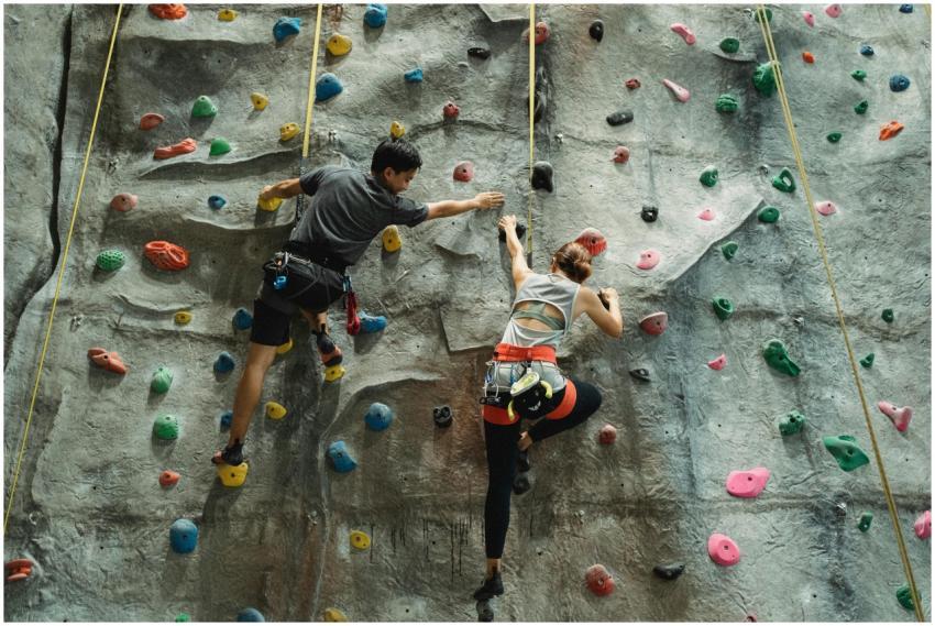 Back view of anonymous strong fearless couple clim