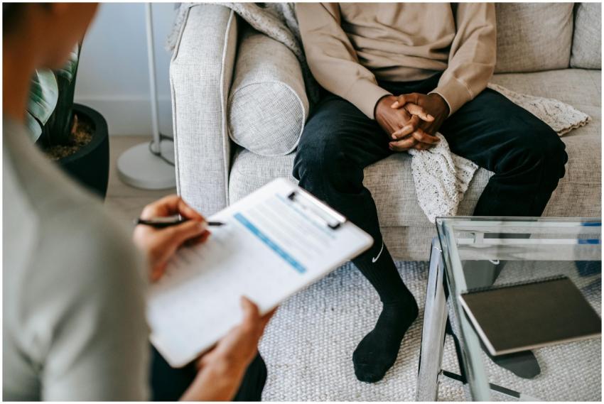 Therapist takes notes as client sits on a sofa dur