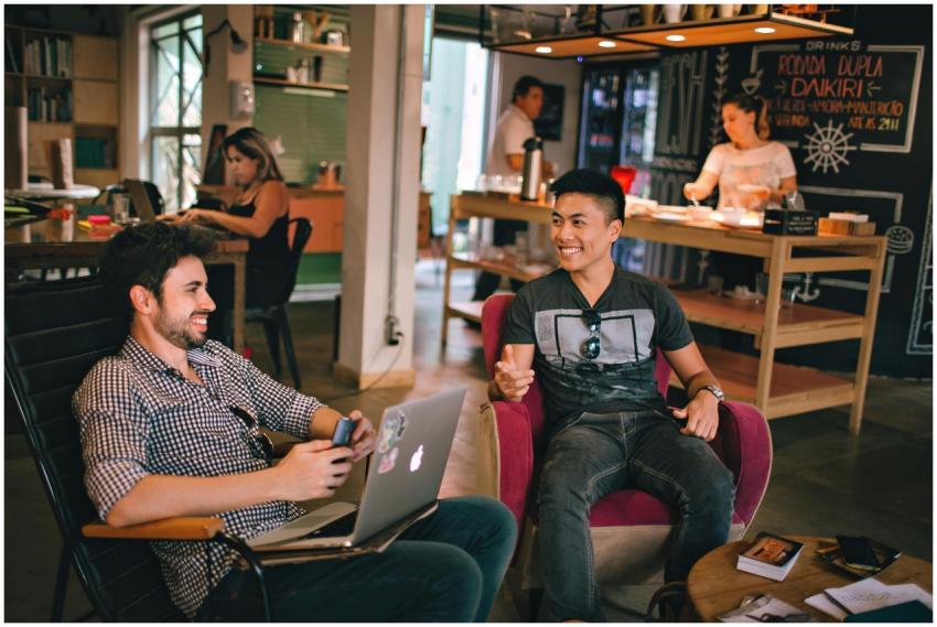 Two men enjoying a relaxed conversation with lapto