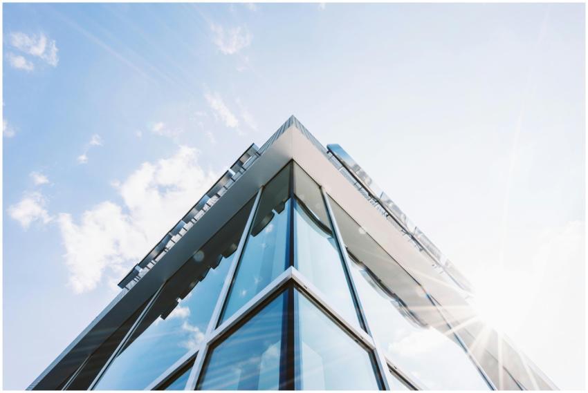 Low angle shot of a modern glass building with sun