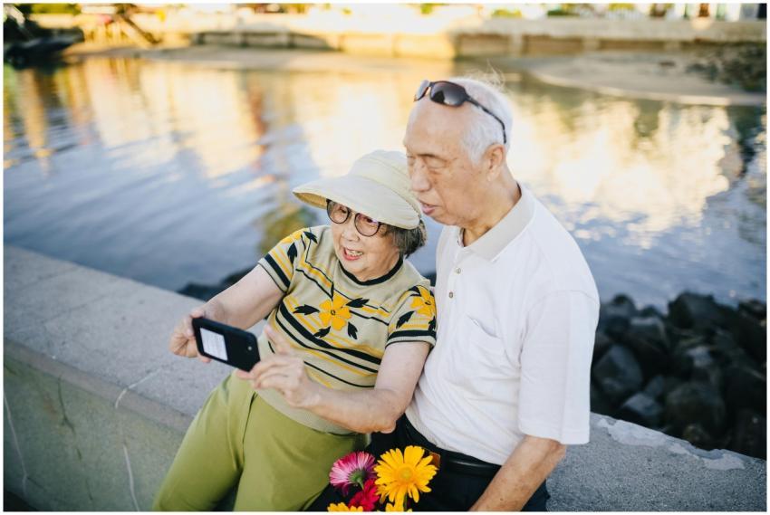 Joyful senior couple taking a selfie by the waterf