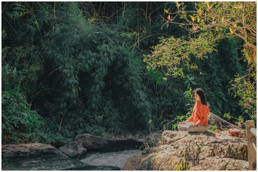 Woman meditating by a serene riverside surrounded