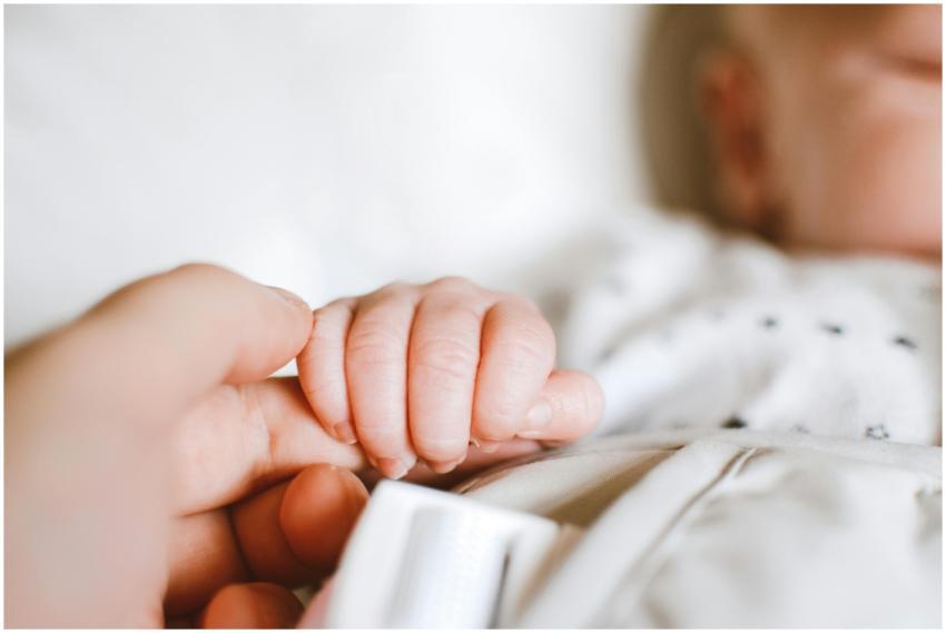 Close-up of a newborn's hand gently gripping a par