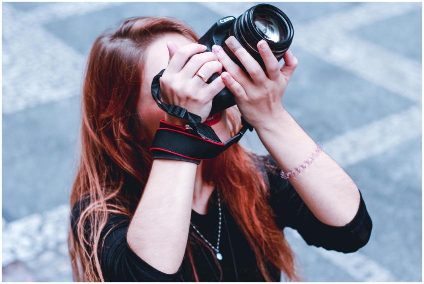 Woman photographing outdoors with camera, focusing
