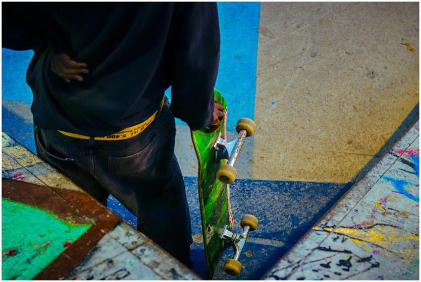 Teenager with skateboard stands ready at colorful