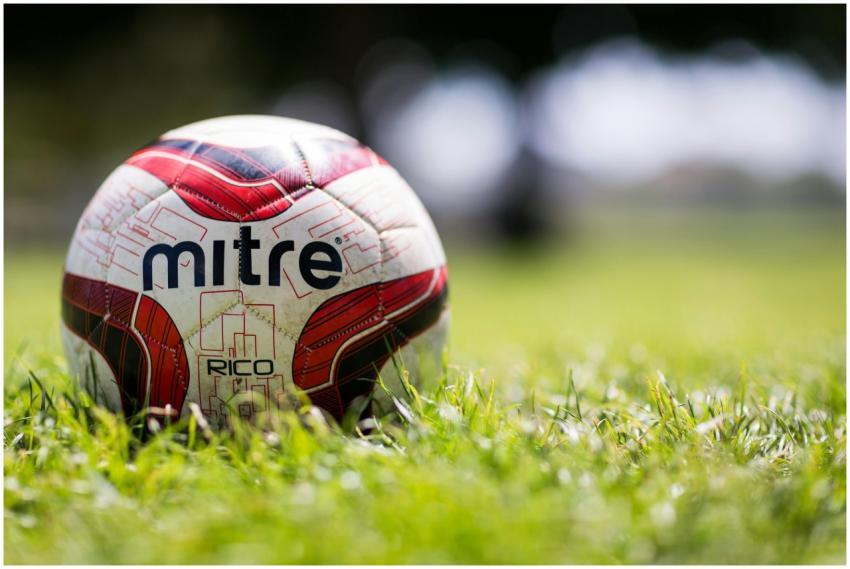 A close-up of a Mitre soccer ball resting on a gra