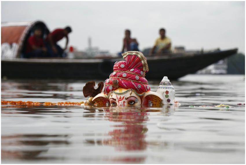 A colorful Ganesha idol partially submerged in a r