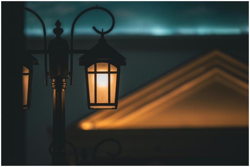 A warm, illuminated street lamp against a soft-foc