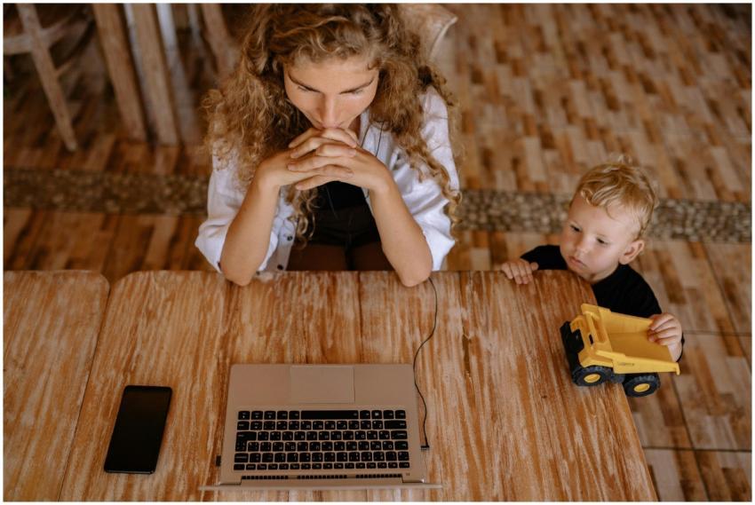A woman works on a laptop at a wooden table with a