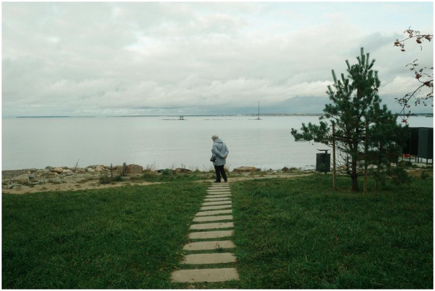 A person walks alone by a serene lake, surrounded