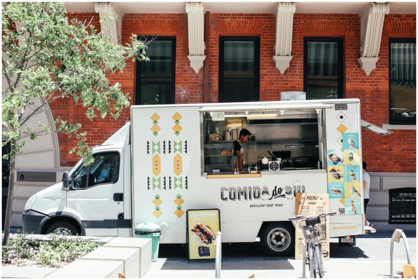 White food truck serving Brazilian cuisine in city
