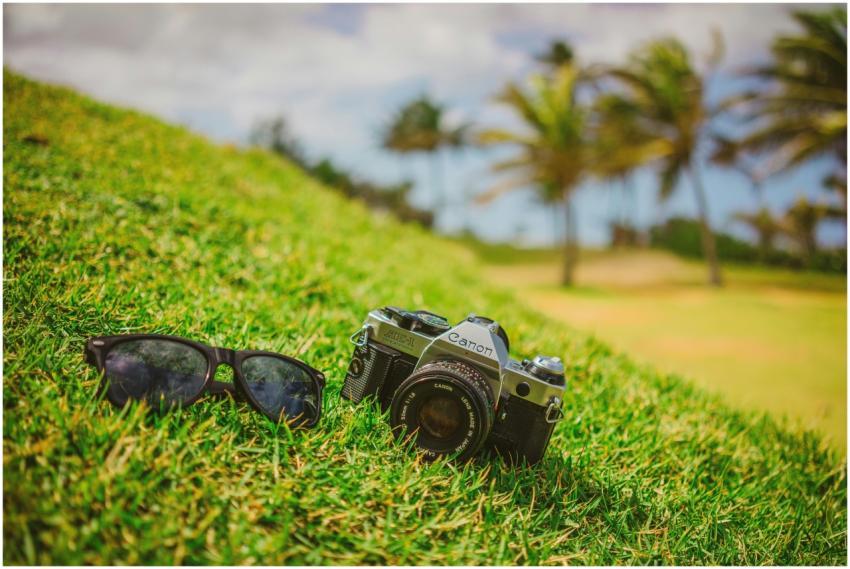 Close-up of a vintage camera and sunglasses on gra