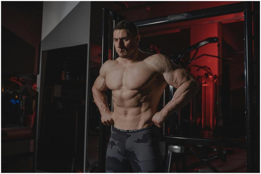 Shirtless bodybuilder flexing muscles under dramat