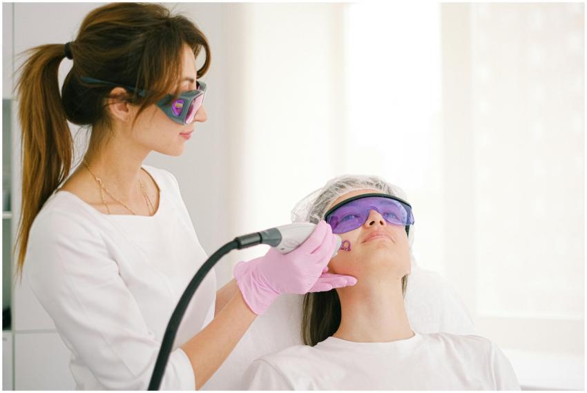 A cosmetologist performing laser treatment on a wo