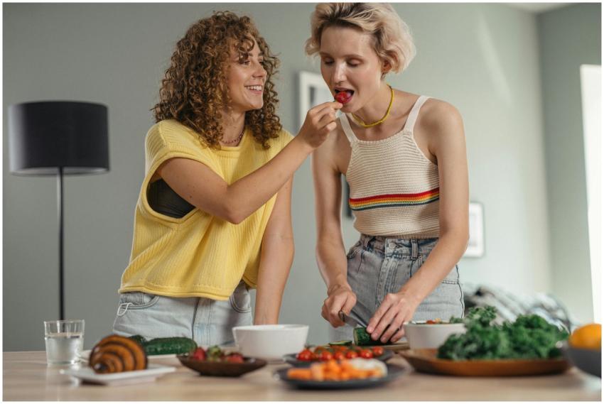 Two women joyfully preparing a meal indoors, highl