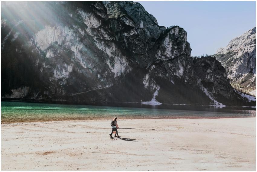 A hiker walks along a serene lakeshore with majest