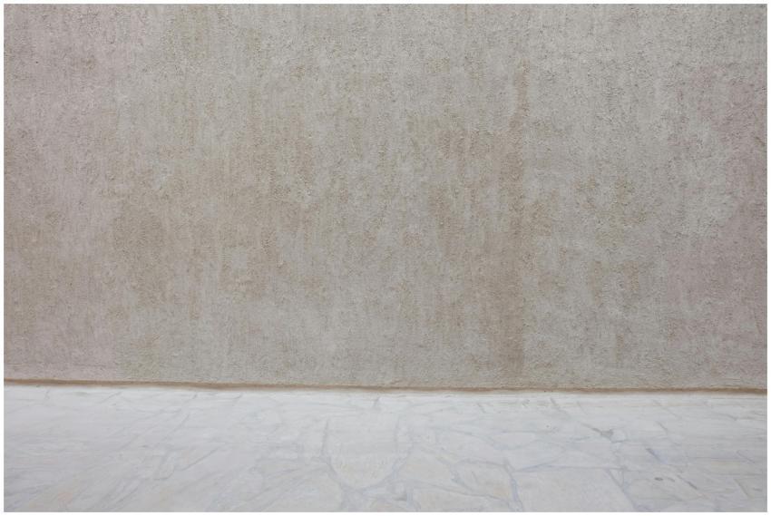 A beige textured wall paired with a stone floor, o