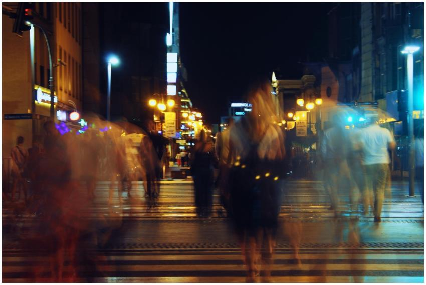 Blurred pedestrians crossing street at night with