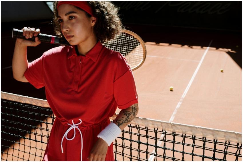 Stylish woman with curly hair holds a racket on a