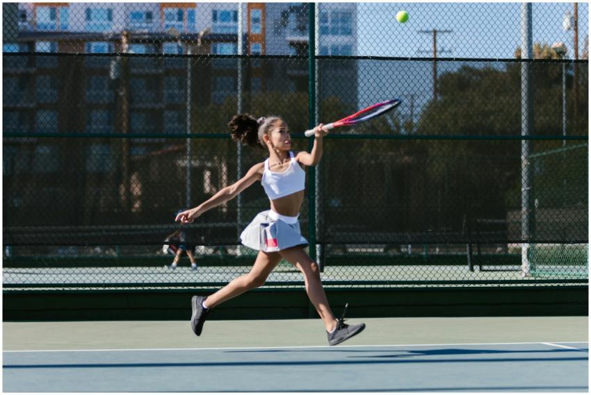 Young girl in activewear playing tennis on a sunny