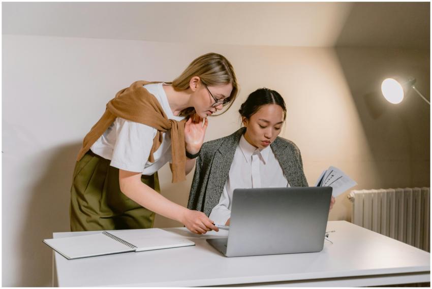 Two women collaborating at a desk with a laptop an