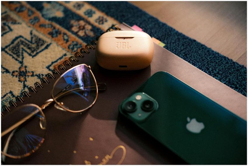 Flat lay of eyewear, smartphone, earbuds, and a no