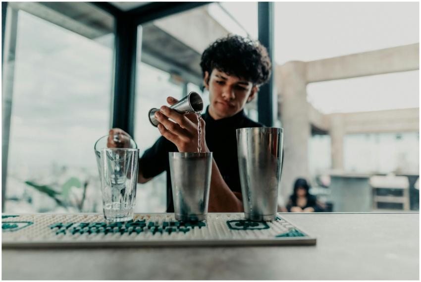 A young bartender skillfully pouring drinks at a s
