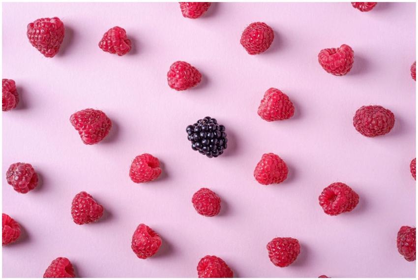 Flat lay of fresh raspberries and a single blackbe