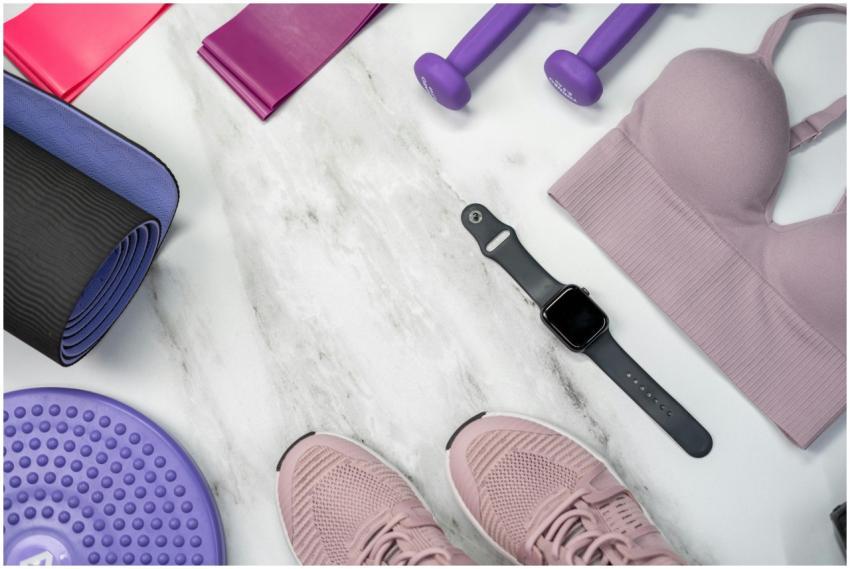 Flat lay of fitness gear including yoga mat, dumbb