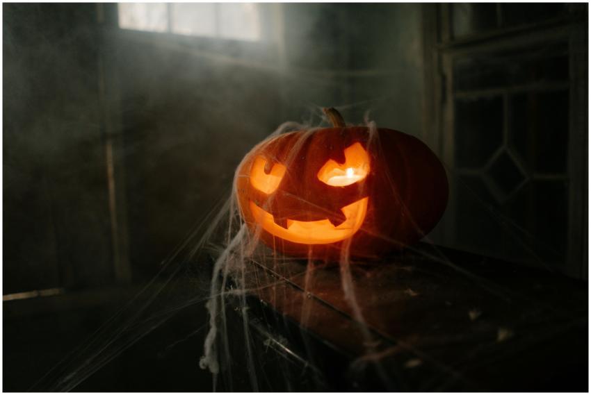 Carved pumpkin jack-o'-lantern illuminated on a sp