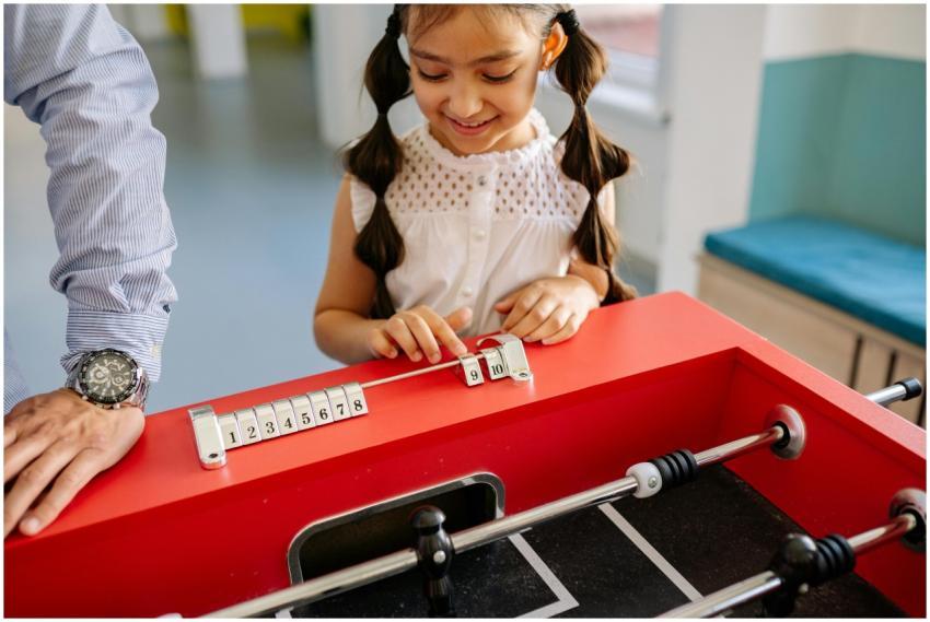 Young girl enjoying a game of foosball in a classr