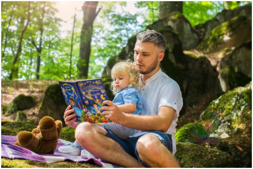 Father and toddler bonding over a book in a sunny