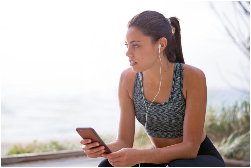 Fit woman with earphones and smartphone taking a b