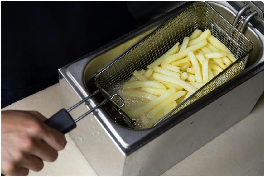 Close-up of french fries being deep-fried in a com