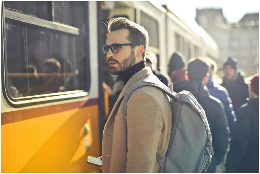 A stylish man with a backpack boards a tram in bus