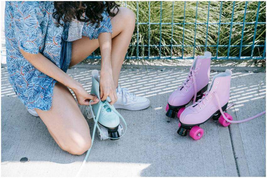 A young adult laces up pastel-colored roller skate