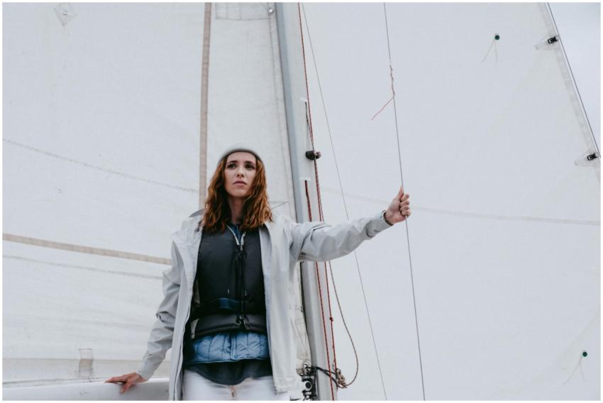 A woman stands confidently on a yacht, enjoying a