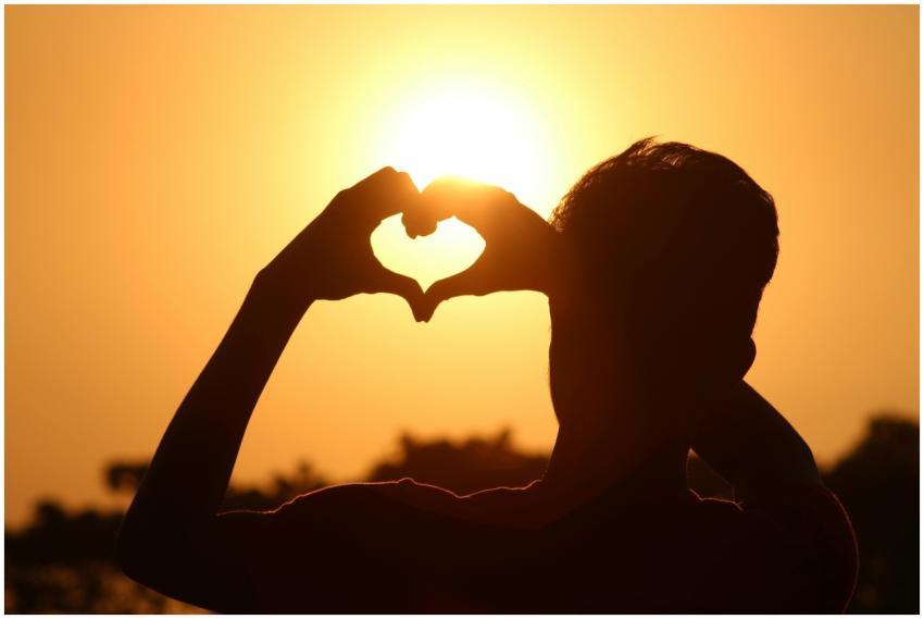 A silhouette of hands forming a heart shape agains