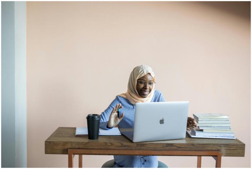 Smiling Muslim woman in hijab waving during an onl