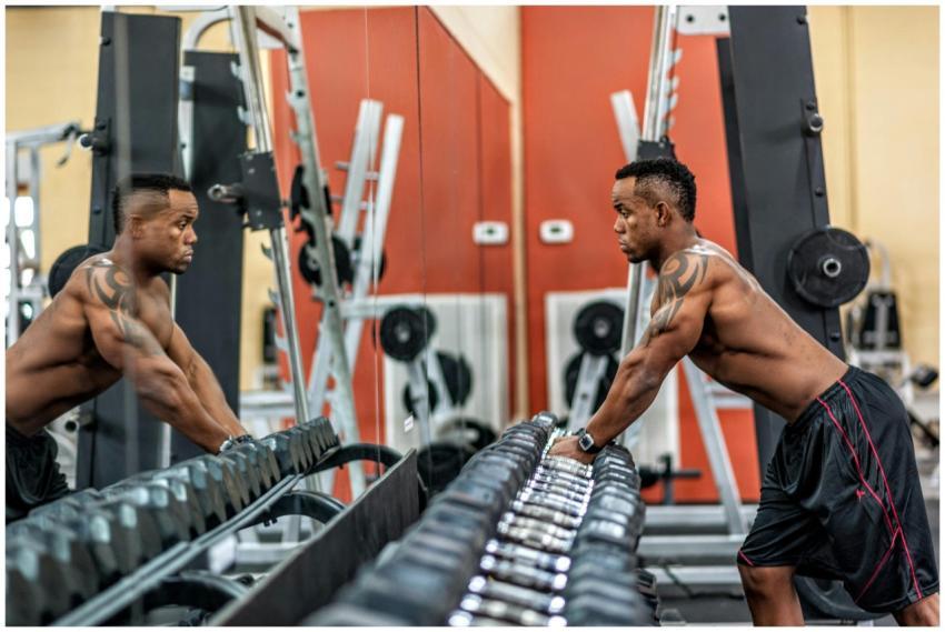 Muscular man exercising with dumbbells in gym, emp