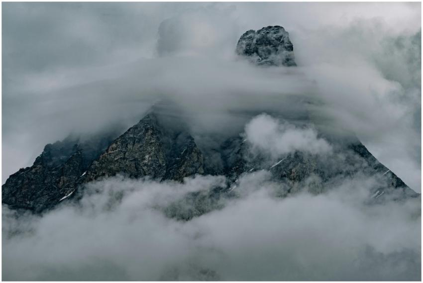 A dramatic photograph of a mountain peak enveloped