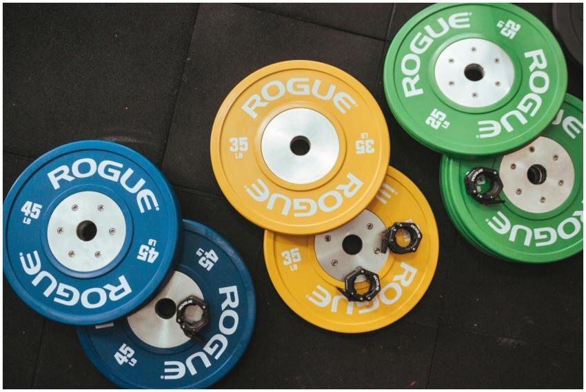 Colorful Rogue weight plates arranged on a gym flo